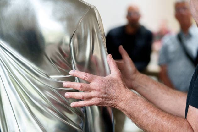 Charles Ray Gives a Press Preview at the Fridericianum in Kassel. Germany - Kassel, 20.08.2026 US sculptor Charles Rays hands are pictured next to his School Play (2014), a larger-than-life solid stainless-steel sculpture, during the press preview of his first institutional solo exhibition in Germany. The exhibition opens to the public on 22 August 2026 and runs until 3 January 2027. Artist: Charles Ray. Ausstellungsansicht Fridericianum, Kassel, 2026. Hesse