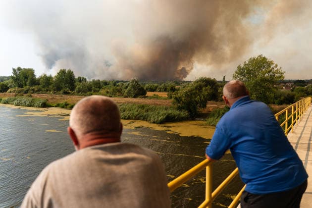 August 20, 2026, Grebenac, Vojvodina, Serbia: 2026820, Grebenac, Serbia - A massive wildfire that has been burning for weeks in the Deliblatska pescara, Special Nature Reserve has reached the village of Grebenac, as locals, firefighters, and military helicopters battle to bring the blaze under control. Local residents stand on a bridge, watching thick plumes of smoke rise from the approaching forest fire. Grebenac Serbia - ZUMAd223 20260820_zip_d223_010 Copyright: xMarkoxDimicx