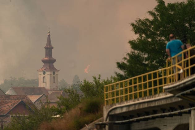 August 20, 2026, Grebenac, Vojvodina, Serbia: 2026820, Grebenac, Serbia - A massive wildfire that has been burning for weeks in the Deliblatska pescara, Special Nature Reserve has reached the village of Grebenac, as locals, firefighters, and military helicopters battle to bring the blaze under control. Onlookers watch from a bridge as open flames burn dangerously close to the village. Grebenac Serbia  - ZUMAd223 20260820_zip_d223_020 Copyright: xMarkoxDimicx