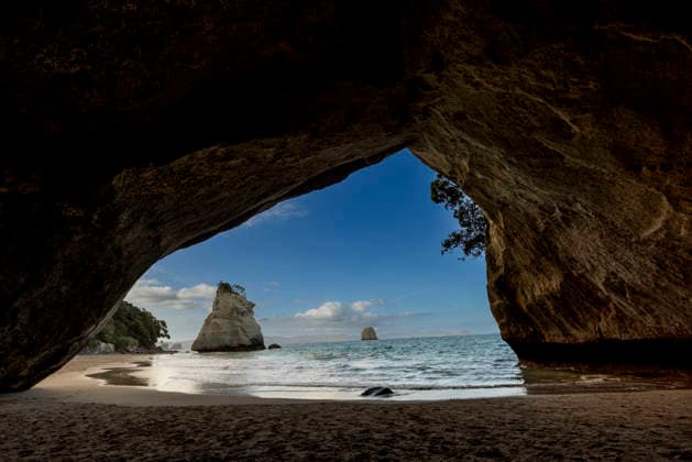View through the tunnel at the sea cave entrance to Cathedral Cove with rock formations and water in the background Copyright: LauraxGrier 1218-2508