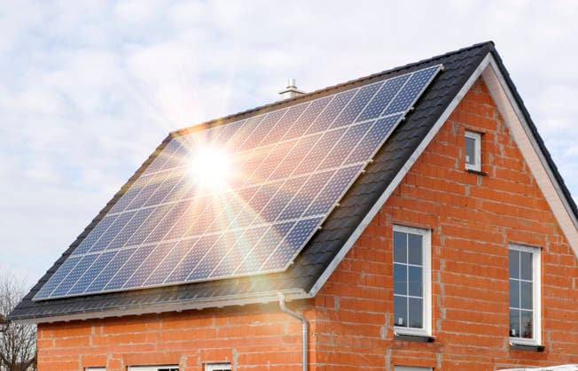 A PV solar system on a house roof A photovoltaic system on the roof of a new house generates green electricity PHOTOMONTAGE FOR EDITORIAL USE ONLY