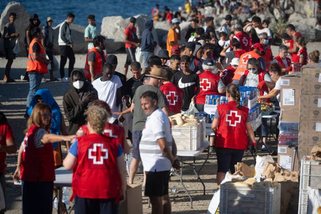 The humanitarian crisis in Ceuta continues. Red Cross members distribute food to migrants on a beach on August 21, 2026, in Ceuta, Spain. Ceuta continues to face a serious humanitarian crisis following the historic mass influx of more than 70,000 migrants who swam across the Tarajal on July 30 and 31. Although the police deployment and border reinforcement by by Moroccan authorities have managed to curb the influx, the autonomous city continues to face a serious humanitarian crisis, health, and security crises. AUGUST 21, 2026 TRAMPOLÍN BEACH MIGRANTS IMMIGRANTS RED CROSS MIGRATION CRISIS Ceuta Ceuta, Spain  Copyright: xMarcosxMorenox 7724966