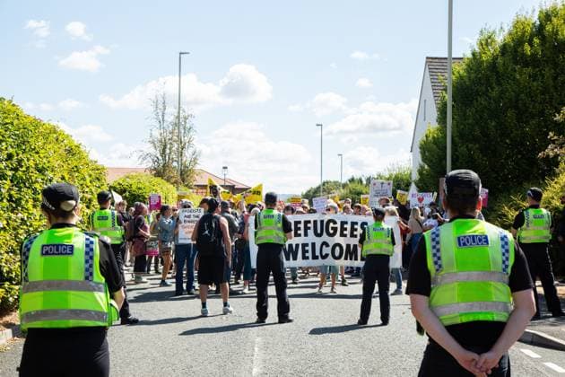 Activist holds pro-refugee sign during Gloucester protest GLOUCESTER, ENGLAND, AUGUST 22, 2026: An activist holds a sign reading Refugees Welcome while walking through a residential street during a protest in Gloucester. The demonstration was held amid debate over the accommodation of migrants in local hotels. Gloucester GB Copyright: x xEthanxFowlerx xJNAxPressx