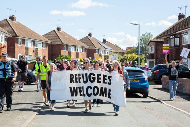 August 22, 2026, Gloucester, GB: GLOUCESTER, ENGLAND, AUGUST 22, 2026: An activist holds a sign reading Ã¢â‚¬oeRefugees WelcomeÃ¢â‚¬Â while walking through a residential street during a protest in Gloucester. The demonstration was held amid debate over the accommodation of migrants in local hotels. Gloucester GB  - ZUMAq101 20260822_zna_q101_124 Copyright: xEthanxFowlerx