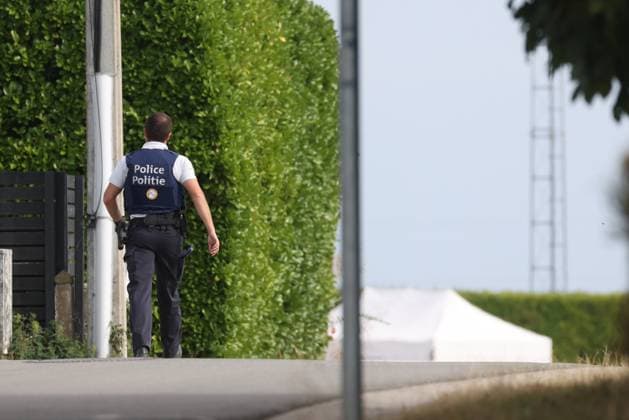 A police officer and a white tent pictured inside a large security perimeter was set by police around Onhaye soccer club, Monday 24 August 2026, in Onhaye.  BRUNOxFAHY 184179978