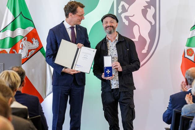 24.08.2026. Düsseldorf. (l-r) NRW-Ministerpräsident Hendrik Wüst und Ralf König bei der Verleihung des Verdienstordens des Landes Nordrhein-Westfalen anlässlich des 80. Landesgeburtstages. Ralf König hat als Autor und Comiczeichner mit seinen gesellschaftskritischen Cartoons Debatten über Sexualität, Religion, Politik und Rollenbilder angestoßen. Seit den 1980er Jahren hat er mit seinen Comics zur sexuellen Aufklärung beigetragen und Tabus aufgebrochen. Mit seinem Engagement für Kunstfreiheit und Menschenrechte hat er zudem gesellschaftliche Verantwortung übernommen. Düsseldorf Staatskanzlei Nordrhein-Westfalen Deutschland *** August 24, 2026, Düsseldorf NRW Minister President Hendrik Wüst and Ralf König at the award cerem