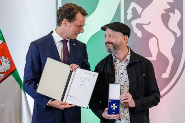 24.08.2026. Düsseldorf. (l-r) NRW-Ministerpräsident Hendrik Wüst und Ralf König bei der Verleihung des Verdienstordens des Landes Nordrhein-Westfalen anlässlich des 80. Landesgeburtstages. Ralf König hat als Autor und Comiczeichner mit seinen gesellschaftskritischen Cartoons Debatten über Sexualität, Religion, Politik und Rollenbilder angestoßen. Seit den 1980er Jahren hat er mit seinen Comics zur sexuellen Aufklärung beigetragen und Tabus aufgebrochen. Mit seinem Engagement für Kunstfreiheit und Menschenrechte hat er zudem gesellschaftliche Verantwortung übernommen. Düsseldorf Staatskanzlei Nordrhein-Westfalen Deutschland *** August 24, 2026, Düsseldorf NRW Minister President Hendrik Wüst and Ralf König at the award cerem