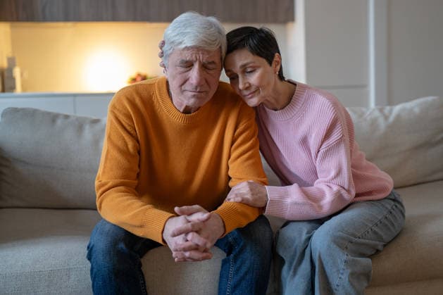 Ein älteres Ehepaar sitzt gemeinsam auf dem Sofa, umarmt sich und gibt sich in dieser schwierigen Zeit gegenseitig Halt. Elderly couple sitting on couch together embracing and supporting each other during difficult time, smiling tranquil woman hugging emotionally tired husband, loving spouse consoling partner on sofa. (License=RF) ,model released, Symbolfoto Copyright: xZoonar.com DmitriixMarchenkox 25431626 ,model released, Symbolfoto ,property released