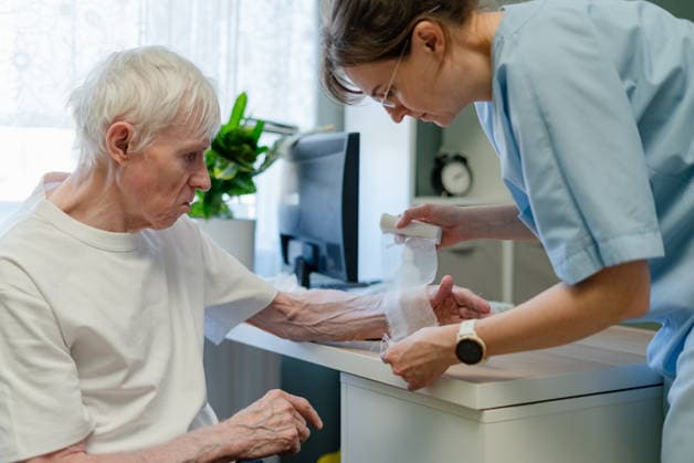 Krankenschwester behandelt einen älteren Mann in einer Hautpflegeklinik Nurse treating elderly man hand in skin care clinic. Healthcare worker providing geriatric dermatology and aging skin treatment for senior patient during thorough medical examination in office (License=RF) ,model released, Symbolfoto Copyright: xZoonar.com ElenaxSkorobogatovax 25445238 ,model released, Symbolfoto ,property released