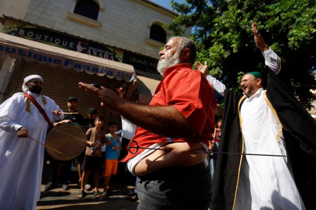 August 25, 2026, Saida, Saidon District, lebanon: Sufi devotees take part in a procession marking the birthday of Prophet Muhammad in the old city of Sidon, Lebanon. The procession began outside the RifaÃ¢â‚¬â ¢i Sufi lodge and moved through the historic streets accompanied by drums, chanting, swords and shields. Some devotees performed the traditional Ã¢â‚¬oeShishÃ¢â‚¬Â ritual, associated with certain RifaÃ¢â‚¬â ¢i Sufi communities, involving the piercing of the body with metal skewers during intense religious chanting. Residents distributed sweets and sprayed rose water as the procession passed. Saida lebanon - ZUMAb339 20260825_znp_b339_014 Copyright: xAbdulxKaderxAlxBayx