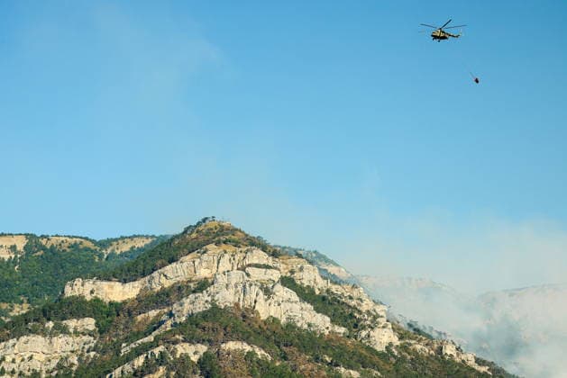 RUSSIA, REPUBLIC OF CRIMEA - AUGUST 26, 2026: A helicopter battles a wildfire in the mountains near Yalta. The blaze, which has been burning for nearly a week, has been declared a regional nature emergency. Maxim Churusov TASS  96651358