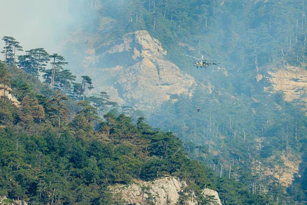 RUSSIA, REPUBLIC OF CRIMEA - AUGUST 26, 2026: A helicopter battles a wildfire in the mountains near Yalta. The blaze, which has been burning for nearly a week, has been declared a regional nature emergency. Maxim Churusov TASS  96651361