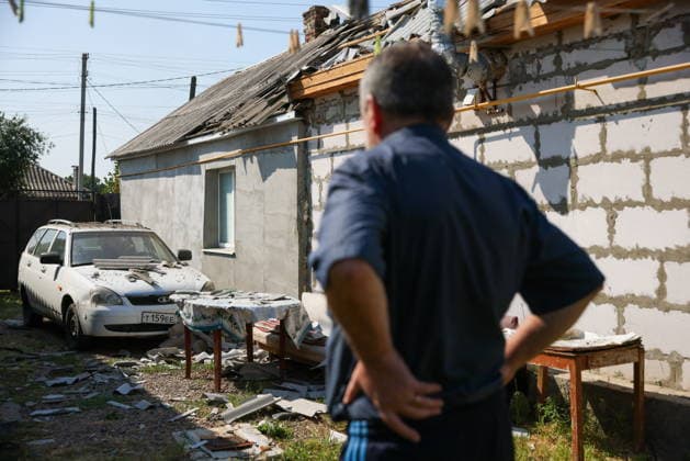 RUSSIA, LUGANSK - AUGUST 26, 2026: A man is seen by a residential house and a car damaged following a strike by the Armed Forces of Ukraine. Alexander Reka TASS  96654851