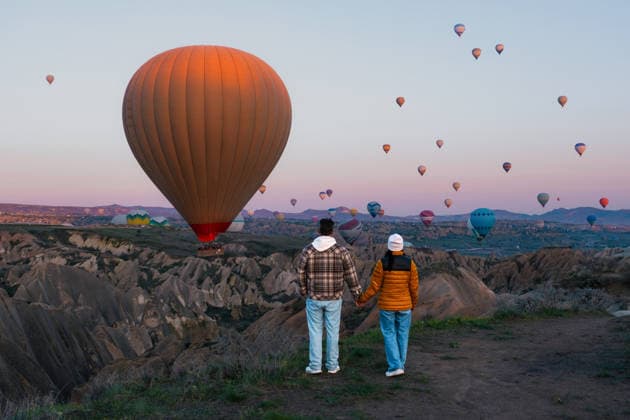 Atemberaubender Blick auf den Sonnenaufgang und die Heißluftballons über der einzigartigen Landschaft Kappadokiens Couple stands hand in hand, gazing at colorful hot air balloons ascending in Cappadocia. The stunning sunrise paints the sky as they enjoy a memorable travel experience in Turkey s enchanting region. (License=RF) ,model released, Symbolfoto Copyright: xZoonar.com FokkexBaarssenx 25481855 ,model released, Symbolfoto ,property released