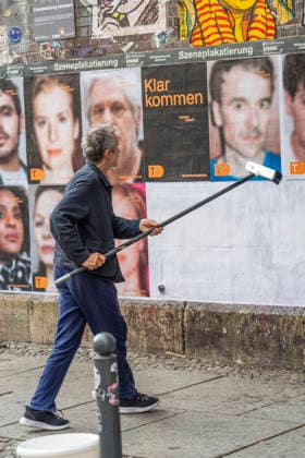 Actor Ulrich Matthes putting up photos featuring actors from the Deutsches Theater on a billboard beneath the Hackescher Markt S-Bahn station in Berlin-Mitte to mark the opening of the 2026–2027 season
