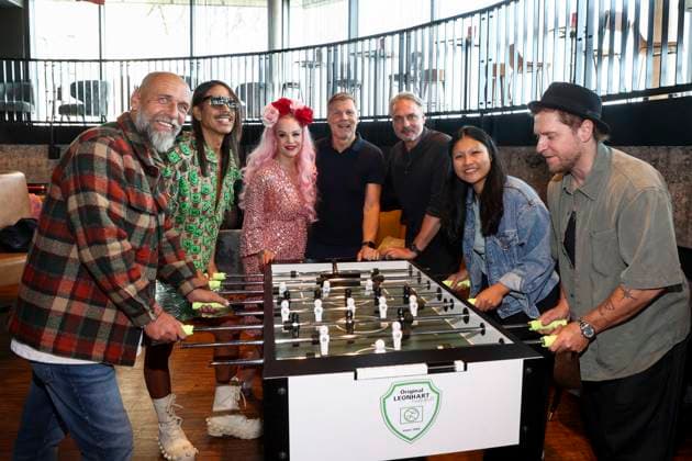 CNTV HERZKICKEN: Holger Stanislawski, Jorge Gonzalez, Belle La Donna, Thomas Helmer, Linh Tran, and Johannes Oerding at the foosball table during the press conference for the Charity Kicken mit Herz event at Restaurant Karo Paul im Bunker, Feldstrasse 27, on August 2026 in Hamburg, Germany