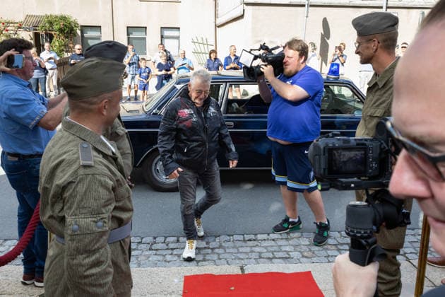 September 5, 2026, movie premiere: Comrade Martin Semmelrogge, who plays the character Mr. Glück, the pharmacist, wearing a mask and a leather jacket, steps onto the red carpet in front of the Markneukirchen Harmonie Lichtspiele movie theater in Saxony, Germany