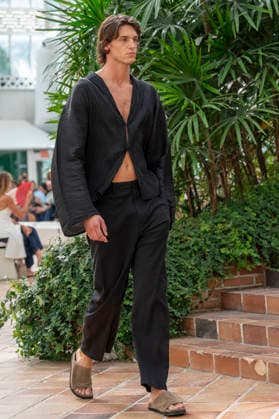 Models present creations from Adolfo Dominguez s Croma collection for spring-summer 2027 during Mercedes-Benz Fashion Week Madrid. Under the creative direction of Tiziana Domínguez, the Galician label, marking its 50th anniversary, remained faithful to its signature codes, showing pronounced asymmetry, scarves worked into both menswear and womenswear, sequins and textile appliques, alongside organic cotton denim dyed in tangerine tones and mini-pleated men s trousers. September 14,2026. (20260914968)