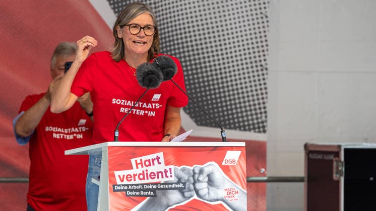 DGB Bavaria: Hard Earned —Large Rally, Nuremberg, September 26, 2026 Christiane Benner, President of IG Metall, speaks with energetic gestures at the podium during a DGB rally. In the background, a participant in a red T-shirt bearing the inscription Savior of the Welfare State applauds. Nuremberg, Bavaria, Germany 20260926-1V9A9981-M4000