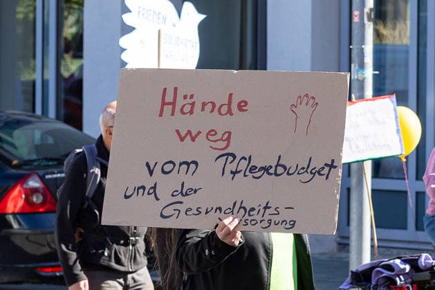 UNKÜRZBAR Protest against attacks on workers’ rights and social infrastructure, Nuremberg, September 26, 2026 A female protester holds up a sign reading Hands off the long-term care budget and health care. In the background, other protest signs featuring peace symbols can be seen. Nuremberg, Bavaria, Germany 20260926-286A8994-M4000