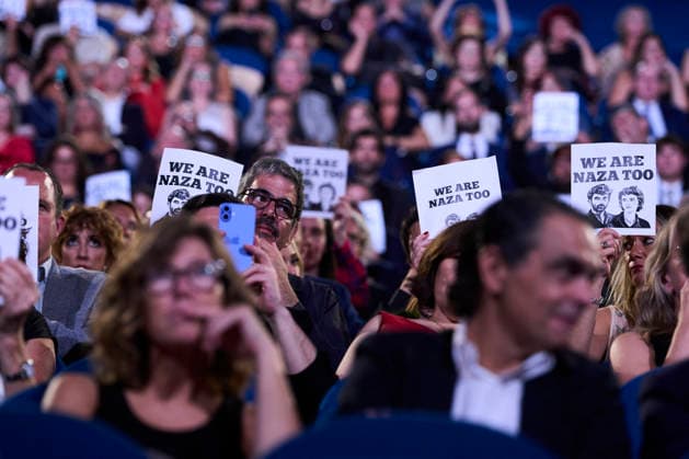 San Sebastian - Closing Ceremony Supporters attended Closing Ceremony Gala during 74th San Sebastian International Film Festival at Kursaal Palace on September 26, 2026 in Donostia San Sebastian, Spain People gather to witness the naza too gala closing on September 26, 2026. A hand holds a white poster with black text reading WE ARE NAZA TOO above two black-and-white illustrated portraits of two men, set against a blurred background of a crowd in dim, purple-toned lighting at the Gala Clausura San Sebastián. Photo by ABACAPRESS.COM Donostia San Sebastian Euskadi Spain  Copyright: xABACAx
