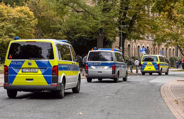 Hanover, Lower Saxony, Germany, Europe Several police emergency vehicles are securing the area around a soccer event. Police vans are parked along the street, while visitors and fans move about in the background. Stock image illustrating security measures, police presence, emergency responders, public order, and large-scale events Copyright: xAymanxAlahmedx