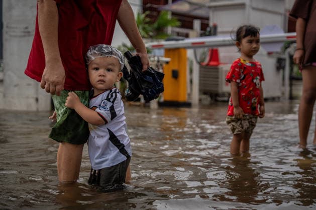 September 27, 2026, Bangkok, Thailand: A child holds on to an adult while standing in floodwater near Phetchaburi Road. Flooding inundated parts of Phetchaburi Road and the Pridi area in Bangkok. Residents waded through the water, vehicles navigated flooded streets, and some drivers parked their cars on an elevated bridge. Bangkok Thailand - ZUMAs197 20260927_aaa_s197_106 Copyright: xPloyxPhutphengx