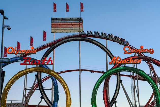 Olympia Looping with a German flag at Oktoberfest, symbolic photo: Munich’s Olympic bid has been approved by the DOSB, Munich, September 27, 2026, Germany, Munich, September 27, 2026: The Olympia Looping roller coaster with a German flag at Oktoberfest; a train travels through t