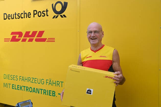 Parcel delivery driver Rudi VAN DEN BOSSCHE is holding a package next to his delivery vehicle; Minister Laumann visits the Deutsche Post and DHL delivery hub in Düsseldorf on September 28, 2026,