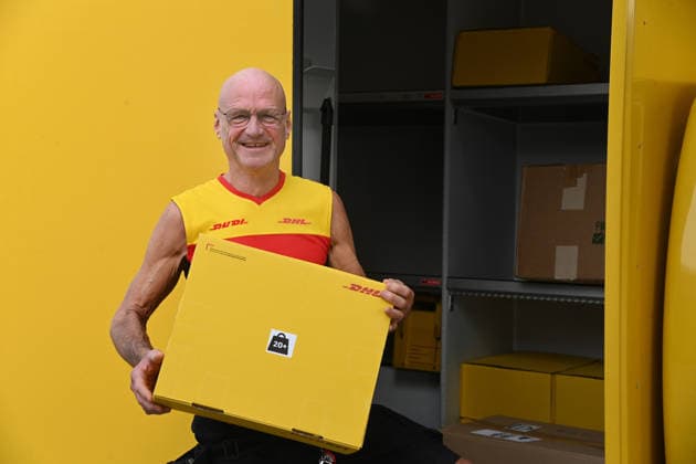 Parcel delivery driver Rudi VAN DEN BOSSCHE is holding a package next to his delivery vehicle; Minister Laumann visits the Deutsche Post and DHL delivery hub in Düsseldorf on September 28, 2026,