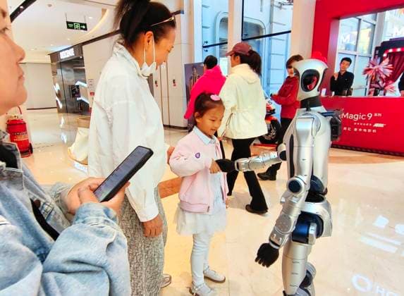 HARBIN, CHINA - SEPTEMBER 29: A humanoid robot shakes hands with children while interacting with customers at a shopping mall on September 29, 2026 in Harbin, Heilongjiang Province of China. Artificial intelligence technologies are increasingly being applied in commercial settings to enhance customer experiences.  Copyright: xVCGx 111670495813