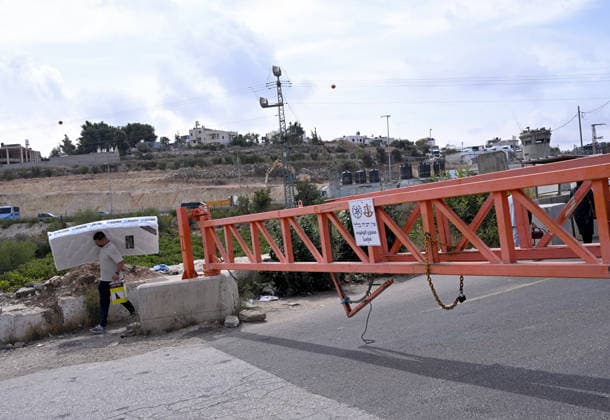 A Palestinian carries a mattress past an Israeli erected locked gate that blocks cars from moving to and from the village of Sair, near Hebron in the West Bank, on Tuesday, September 29, 2026. Israel declared a West Bank military closure to restrict Palestinian movement during the Jewish holiday of Sukkot from September 27 - October 3, 2026.  JER2026092901 DEBBIExHILL