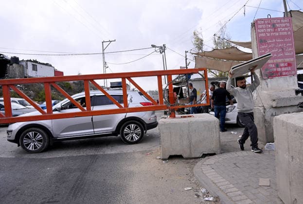 A Palestinian carries a table past an Israeli erected locked gate that blocks cars from moving to and from the village of Halhul, near Hebron in the West Bank, on Tuesday, September 29, 2026. Israel declared a West Bank military closure to restrict Palestinian movement during the Jewish holiday of Sukkot from September 27 - October 3, 2026.  JER2026092908 DEBBIExHILL