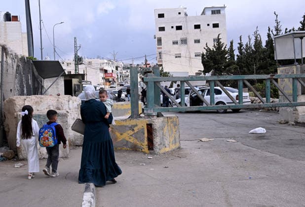 A Palestinian walks with her children past an Israeli erected locked gate that blocks cars from moving to and from the village of Sair, near Hebron in the West Bank, on Tuesday, September 29, 2026. Israel declared a West Bank military closure to restrict Palestinian movement during the Jewish holiday of Sukkot from September 27 - October 3, 2026.  JER2026092906 DEBBIExHILL