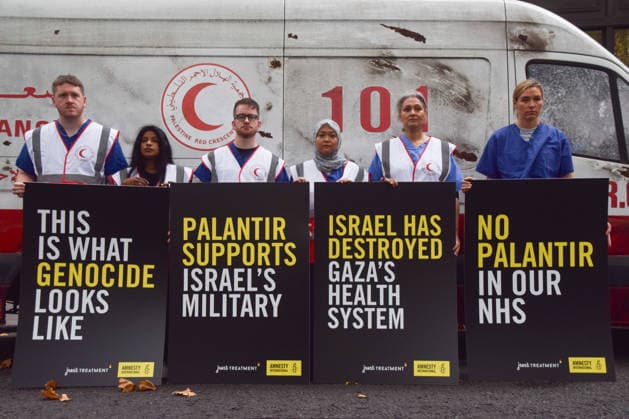 September 30, 2026, London, England, United Kingdom: Healthcare professionals stand with placards next to a van made to look like a heavily damaged Gaza ambulance as Amnesty International UK and Just Treatment stage a protest outside Palantir headquarters in Soho Square. The campaigners are calling on the UK Government not to extend its NHS contract with the US tech company. London United Kingdom - ZUMAv130 20260930_zip_v130_007 Copyright: xVukxValcicx