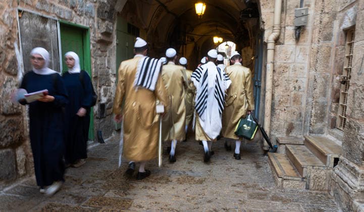 Ultra-Orthodox Jewish men pass two Moslem women who make their way into the Haram al Sharif, or Temple Mount, where the al-Aqsa Mosque is located, as Jews hold mass prayers in the Moslem Quarter in Jerusalem s Old City on Wednesday, September 30, 2026. During the week of Sukkot, or the Feast of Tabernacles, Thousands of Jews, mostly ultra-Orthodox, pack a street leading to a gate, which was closed, leading into the Temple Mount or the á¸¤aram al Sharif where the Al Aqsa Mosque is located.  JER20260930009 JimxHollander