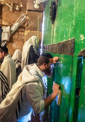 An ultra-Orthodox Jewish man holds a prayer book as he peers through a crack in a grate leading into the Temple Mount or the á¸¤aram al Sharif where the Al Aqsa Mosque is located, during prayers during the Holy Week of Sukkot, or the Feast of Tabernacles, in the Moslem Quarter in Jerusalem on Wednesday, September 30. 2026 Thousands of Jews, mostly ultra-Orthodox, packed a street leading to a gate, which was closed, leading  JER20260930011 JimxHollander