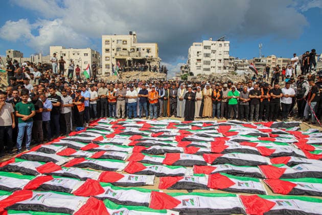 Gaza Mass Funeral For Victim A large crowd of Palestinian mourners stands around tightly arranged rows of shrouded remains draped in Palestinian flags beside rubble and damaged buildings in Gaza City, Gaza Strip, on October 1, 2026. Gaza Civil Defense said the funeral was held for the remains of 105 people recovered from beneath the rubble of the Al-Taj residential complex and surrounding buildings in the Al-Yarmouk area, which were destroyed in Israeli strikes on October 25, 2023. The remains were taken for burial at Sheikh Radwan cemetery. Gaza Gaza Strip Palestinian Territories Copyright: xRamezxHabboubx