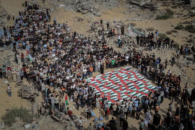 Gaza Funeral For Recovered Victims A high-angle view shows a dense crowd encircling rows of Palestinian flag-draped shrouds laid out on the ground amid rubble in Gaza City, Gaza Strip, on October 1, 2026. Gaza Civil Defense said the remains were among those of 105 Palestinians recovered during a 17-day search of the Al-Taj residential block in the Al-Yarmouk area, which was struck by Israel on October 25, 2023. Gaza City Gaza Strip Palestinian Territories Copyright: xMohammedxMxSkaikx