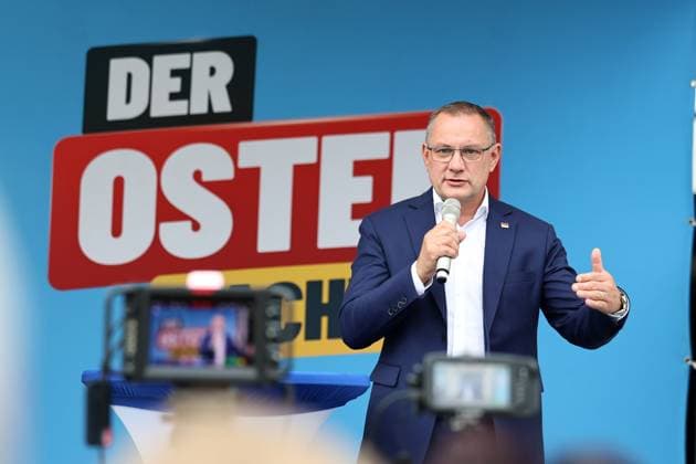 Enjoying a Bratwurst with Haseloff and Chrupalla, October 1, 2026, Doellstaedt, AfD event at Kiesling Roofing; enjoying a bratwurst with state parliament member Daniel Haseloff (AfD) and AfD national spokesperson Tino Chrupalla. Pictured: Tino Chrupalla giving a speech on stage, with the phrase The East is doing it in the background.