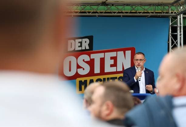 Enjoying a Bratwurst with Haseloff and Chrupalla, October 1, 2026, Doellstaedt, AfD event at Kiesling Roofing, Enjoying a bratwurst with State Parliament Representative Daniel Haseloff (AfD) and AfD National Spokesperson Tino Chrupalla; pictured: Tino Chrupalla giving a speech on stage, with the phrase The East is doing it in the background
