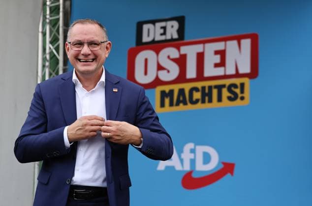 Enjoying a Bratwurst with Haseloff and Chrupalla, October 1, 2026, Doellstaedt, AfD event at Kiesling Roofing, Enjoying a bratwurst with State Parliament Representative Daniel Haseloff (AfD) and AfD National Spokesperson Tino Chrupalla; pictured is Tino Chrupalla, with the phrase The East is doing it in the background