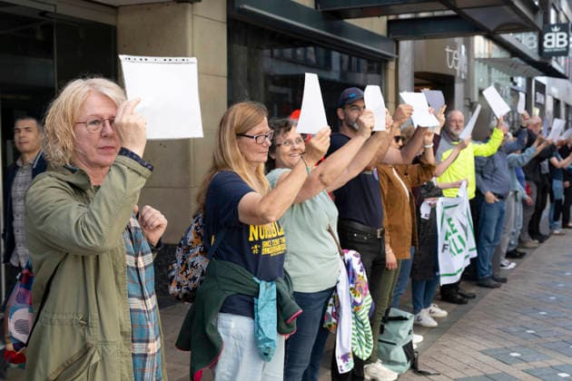 October 3, 2026 Press event: Es brennt initiative—human chain in Dortmund, Hansaplatz; participants on Westenhellweg hold up white paper; Dortmund, Hansaplatz and Westenhellweg, North Rhine-Westphalia, Germany