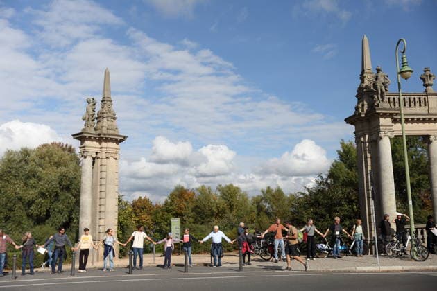 Protesters during a human chain for climate protection and democracy on the Glienicker Bridge in Potsdam, October 3, 2026. It s on fire —human chain in Potsdam