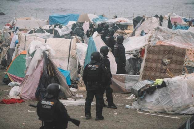 October 4, 2026, Ceuta, Ceuta, Spain: Riot police officers stand among the shelters of the makeshift migrant camp on El Trampolin beach in Ceuta during the eviction. Spanish National Police began evicting the makeshift camp on El Trampolin beach in Ceuta on October 4, where more than 3,000 migrants, most of them young Moroccan men, were living. Dozens of police vans, armoured vehicles of the Police Intervention Units (UIP), drones and boats took part in the operation. People were taken by bus to the temporary centre at the Tarajal border to be identified, and the authorities plan to clear the beach in phases before October 15. The camp grew after a mass arrival at the end of July 2026 set off a migration and political crisis. Ceuta Spain - ZUMAs392 20261004_zip_s392_006 Copyright: xFabianxSuspensivox