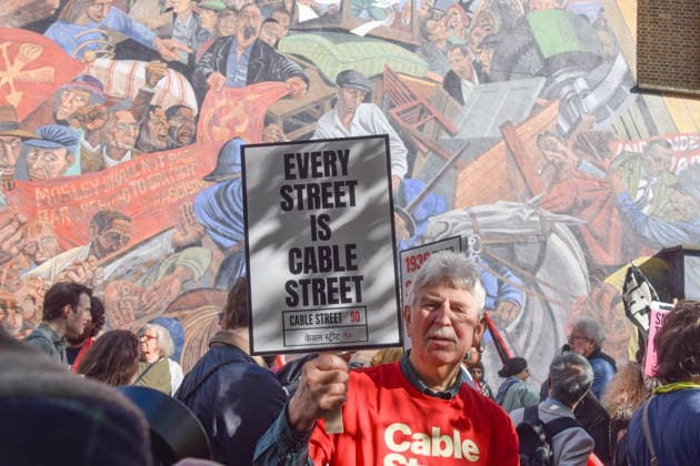 October 4, 2026, London, England, United Kingdom: Protesters pass by the Cable Street Mural, painted by Dave Binnington, Paul Butler, Ray Walker and Desmond Rochfort between 1979 and 1983, during the march against racism and fascism, marking the 90th anniversary since the Battle of Cable Street. London United Kingdom - ZUMAv130 20261004_zip_v130_071 Copyright: xVukxValcicx
