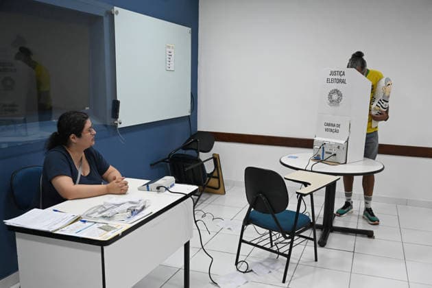 (261004) -- BRASILIA, Oct. 4, 2026 -- A voter (R) casts his ballot at a polling station in Brasilia, Brazil, Oct. 4, 2026. Voting in the first round of Brazil s 2026 presidential election officially began at 8 a.m. (1100 GMT) on Sunday, with polling stations across the country scheduled to close at 5 p.m. (0800 GMT). Initial results are expected to be announced within a few hours after the polls close. (Photo by Xinhua) BRAZIL-PRESIDENTIAL ELECTION-FIRST ROUND-VOTING LucioxTavora 