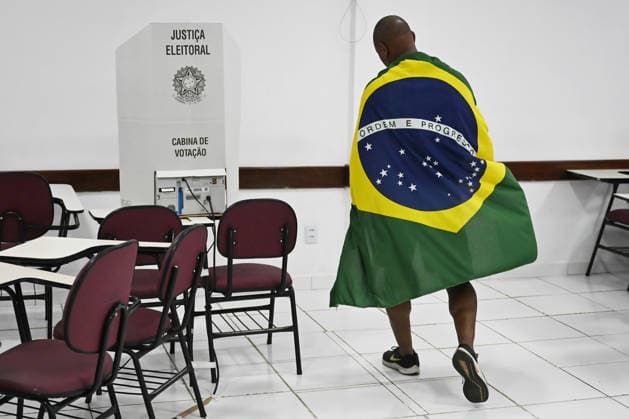 (261005) -- BRASILIA, Oct. 5, 2026 -- A voter draped in a national flag is pictured at a polling station in Brasilia, Brazil, Oct. 4, 2026. (Photo by Xinhua) Photo Flash Lula, Flavio Bolsonaro head to runoff in Brazil presidential election LucioxTavora 