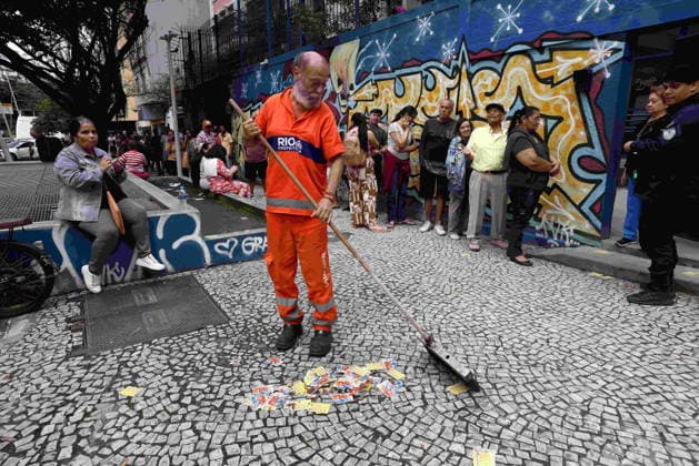 October 4, 2026, Rio De Janeiro, Rio De Janeiro, Brazil: A Comlurb city sanitation worker sweeps up campaign stickers and pamphlets as voters wait in line outside Escola Municipal MaroÂlia de Dirceu, a polling place in Rio de Janeiro, Brazil, on Election Day, as millions of citizens head to the polls in the countryâ€⠢s closely contested 2026 general election. The presidential race between incumbent Luiz Ino¡cio Lula da Silva and right-wing Senator Flo¡vio Bolsonaro has dominated the campaign, with polls showing a tight contest ahead of the October 4 first round. Brazilians are also voting for governors, senators and federal and state legislators. Rio De Janeiro Brazil - ZUMAn Li 20261004_znp_k251_004 Copyright: xBobxKarpx