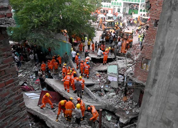 NEW DELHI, INDIA - OCTOBER 7: National Disaster Response Force (NDRF) jawans, Delhi Fire Service personnel, and local residents navigate heavy rubble during a search and rescue operation after a four-storey residential building collapsed in the New Seemapuri area of Shahdara on October 7, 2026, in New Delhi, India. The structural collapse occurred around 3:30 PM behind the local fish market, trapping multiple residents under concrete slabs and damaging two adjoining houses. At least one minor died while eight people were rescued and rushed to Rajiv Gandhi Super Speciality Hospital for emergency medical treatment as sniffer dogs and excavators worked late into the evening to locate remaining trapped survivors. (Photo by Ishant Chauhan Hindus